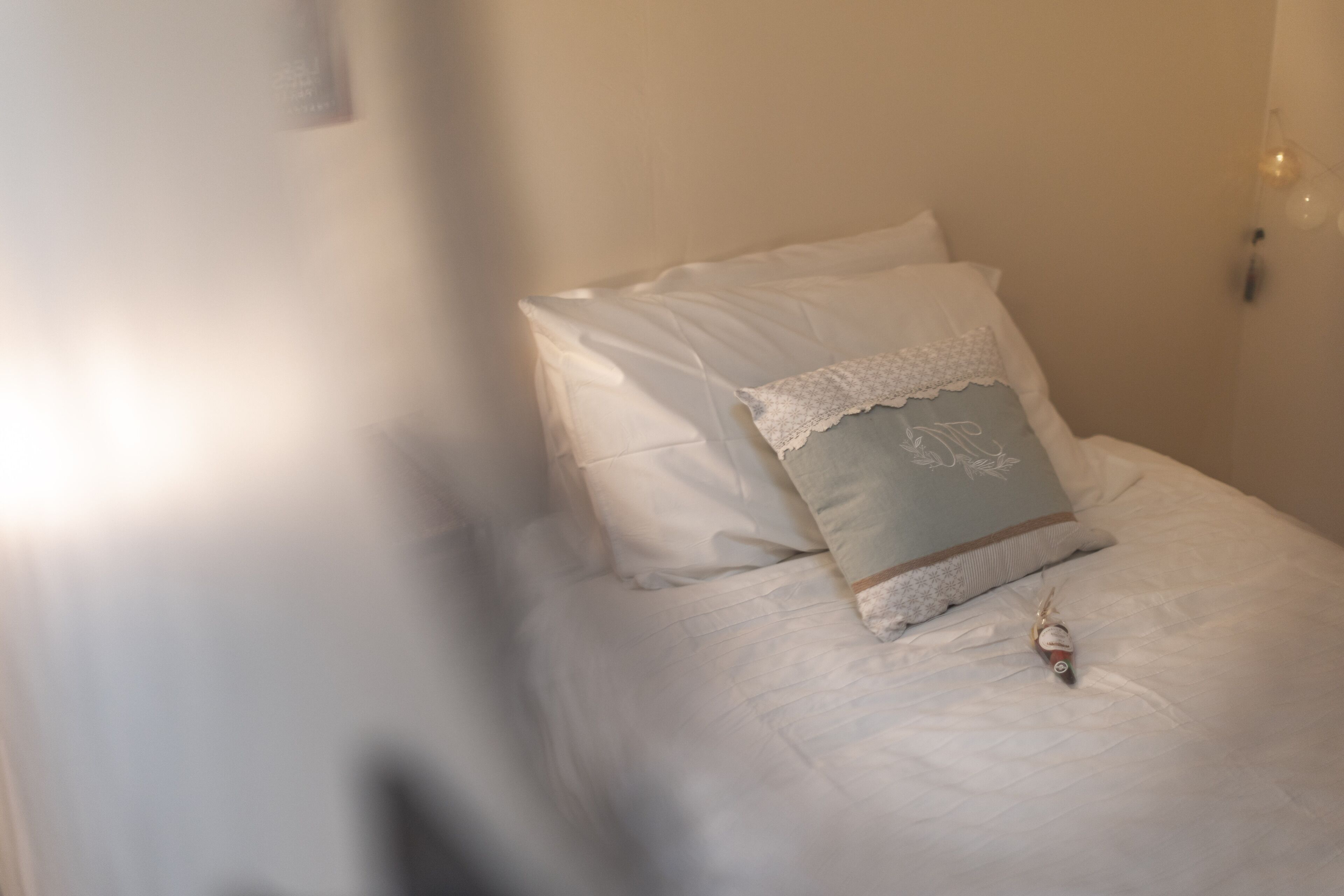 A neatly made bed with white linens and a lace-trimmed pillow.