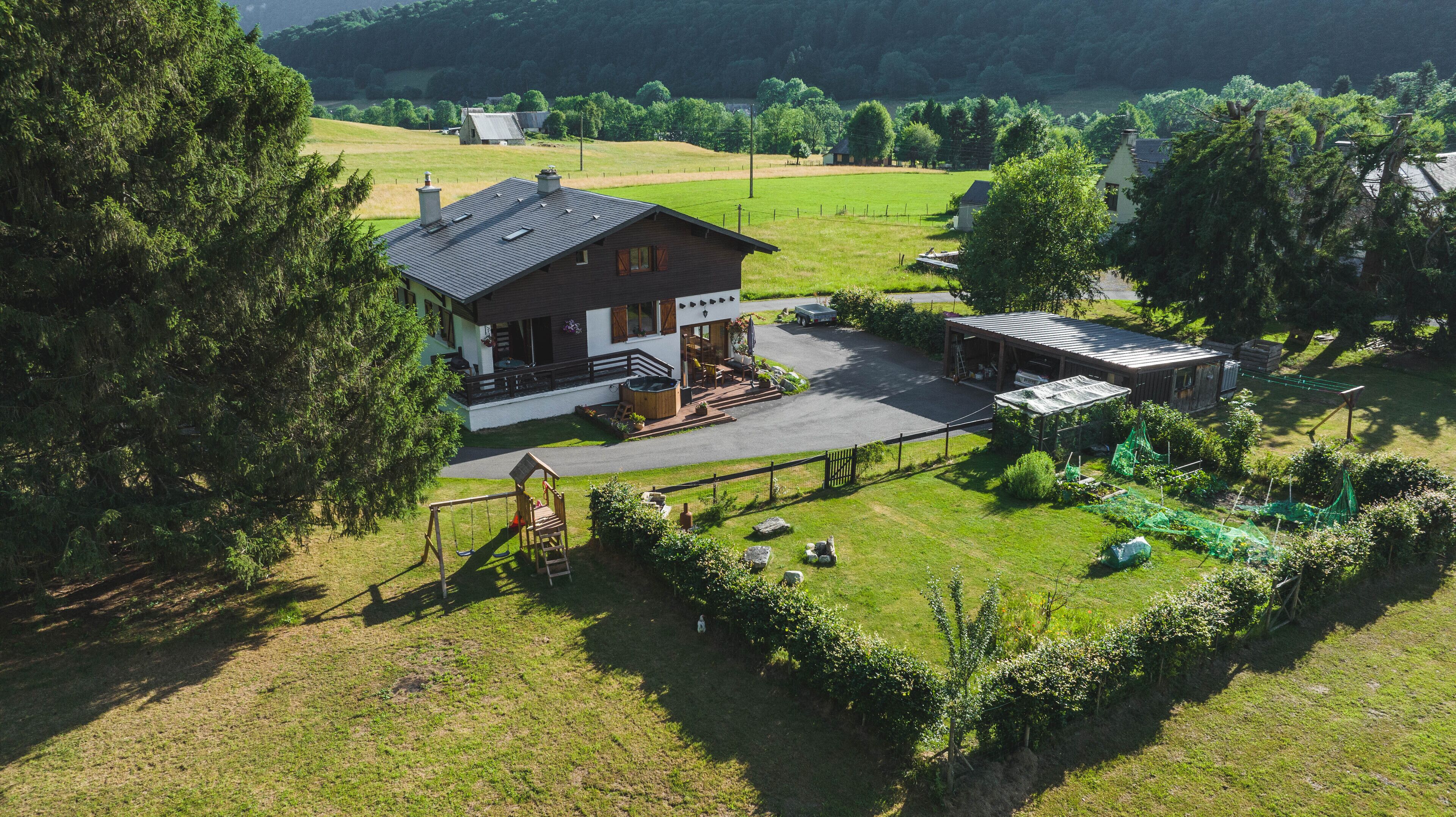 A large house with a porch, a garage, and a fenced garden area.