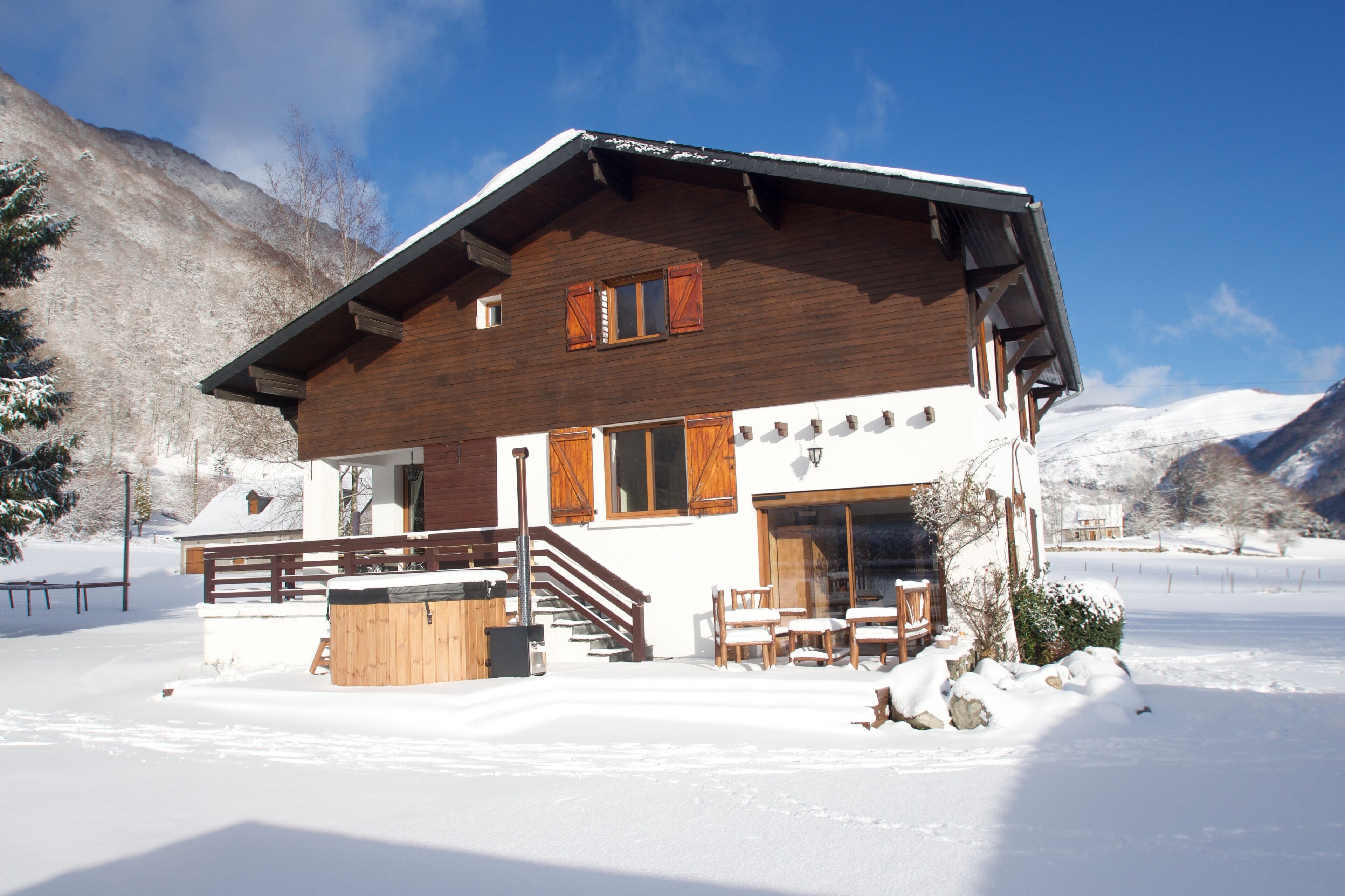 Eine Holzchalet mit Balkon, Whirlpool und einer Seilbahn im Hintergrund.