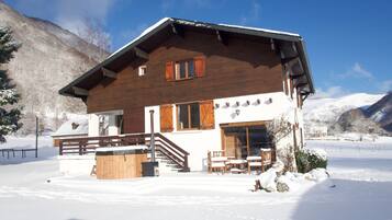 Eine Holzchalet mit Balkon, Whirlpool und einer Seilbahn im Hintergrund.