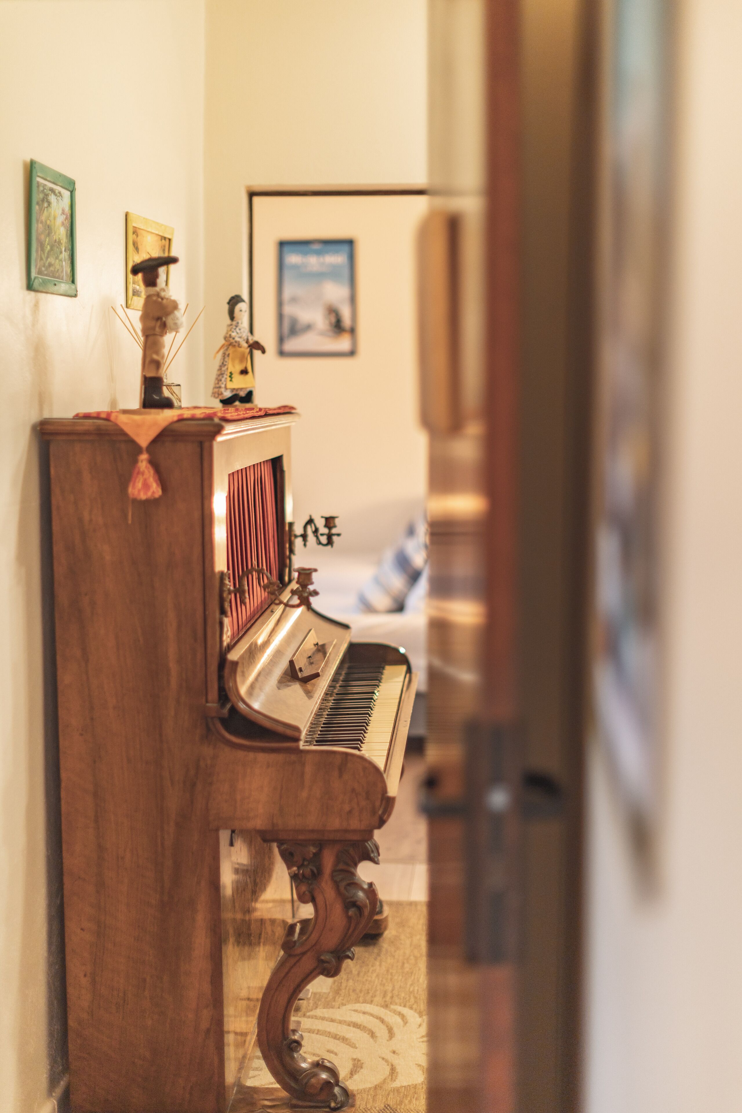 Un piano de madera en una habitación con una cama y un cuadro en la pared.