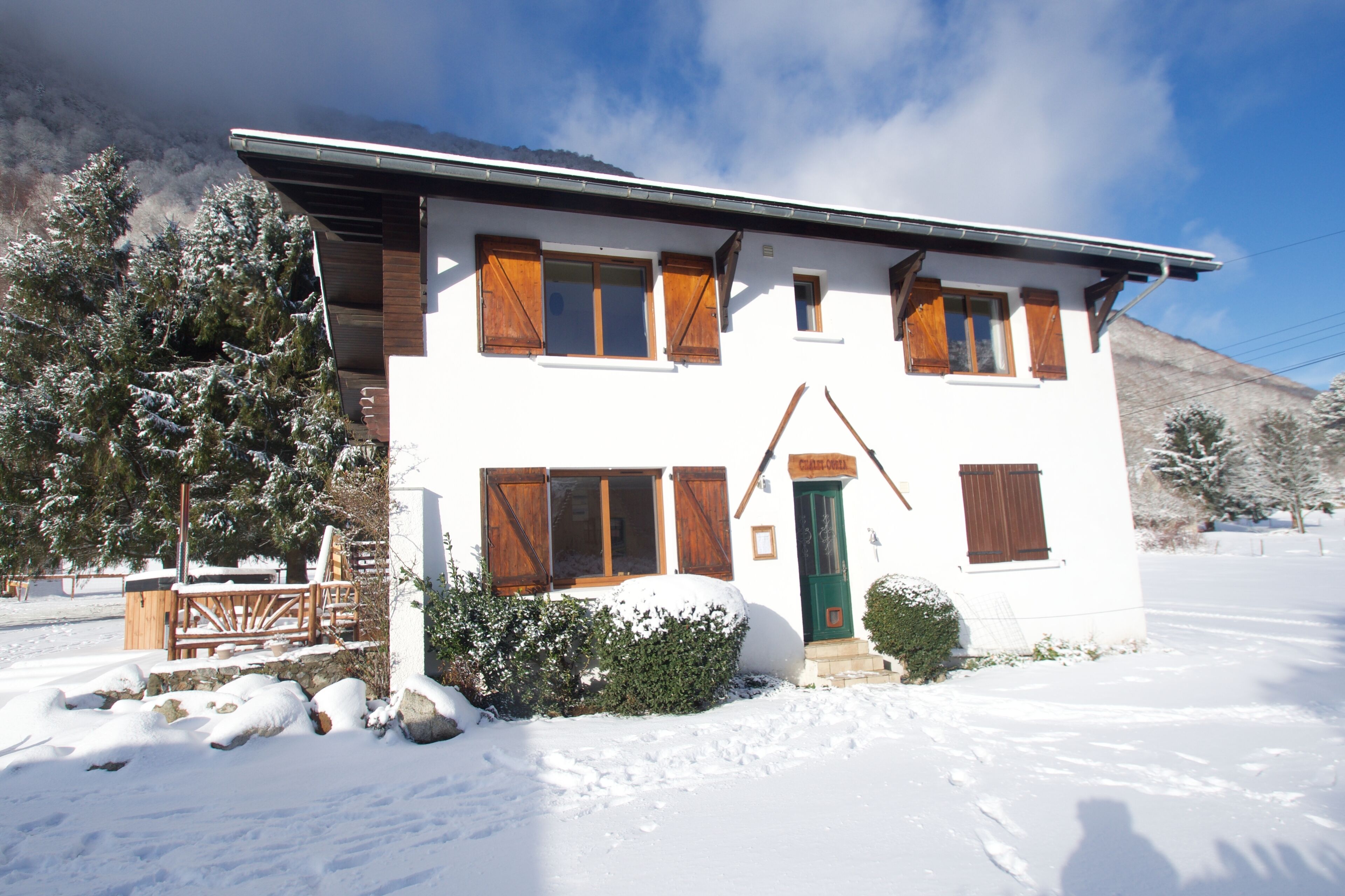 A two-story building with wooden shutters, a green door, and a snow-covered landscape.