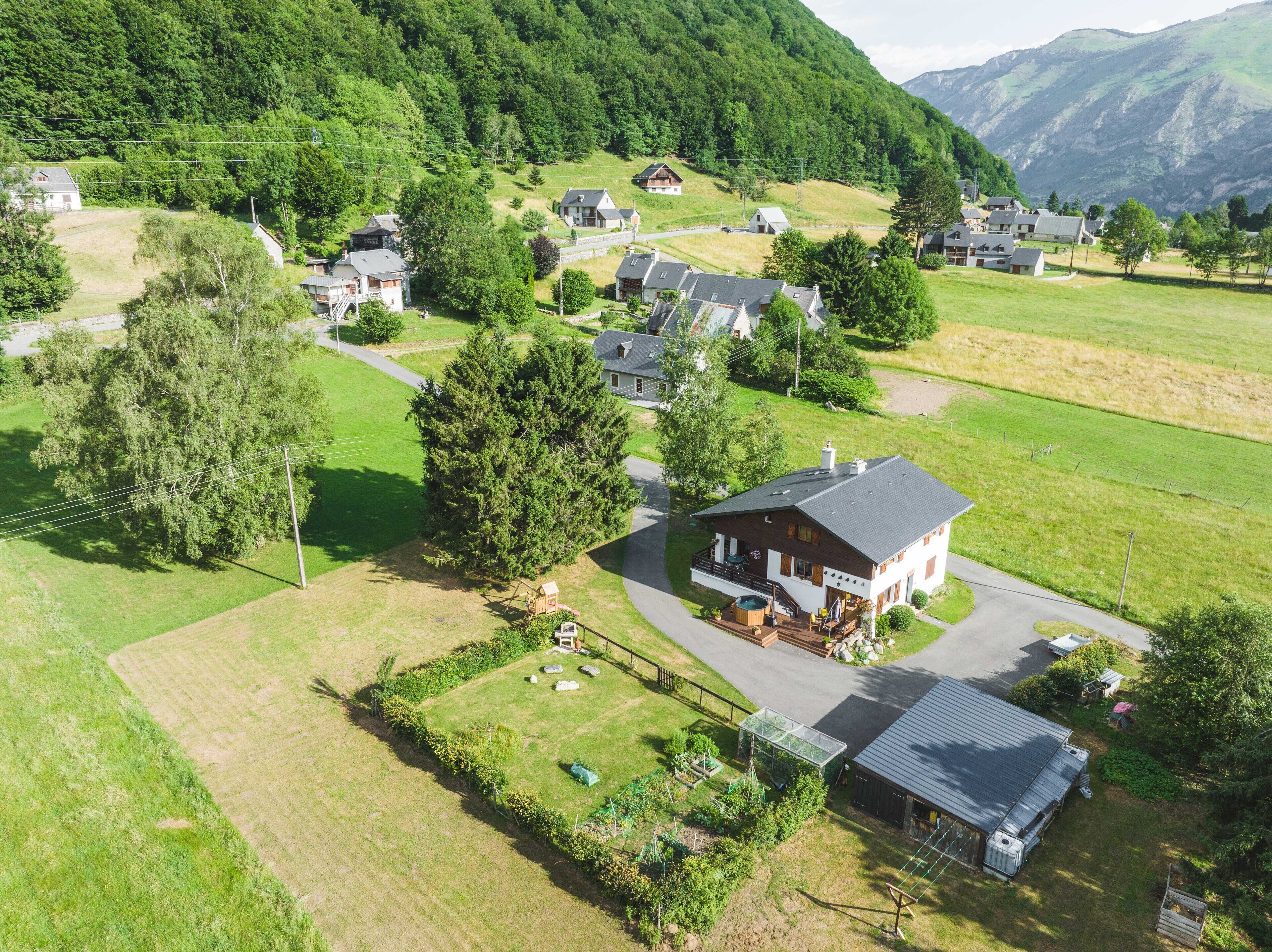 Vista aérea de un pueblo rural con casas rodeadas de campos verdes y montañas.