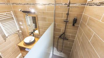 A modern bathroom with a glass shower enclosure, a wooden vanity, and a white towel rack.