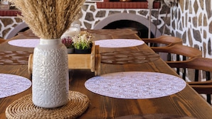 A rustic dining area with a wooden table, woven placemats, and a vase with dried plants. - Villa Fisi 1 - Pool, Hot Tub & Mountain View (Mylopotamos)
