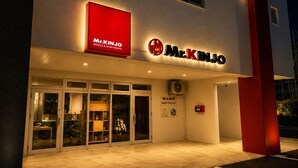 A hotel entrance with a prominent red sign, glass doors, and a visible fire alarm. - Mr.KINJO Miyakojima Aparagi Resort 1 (Miyakojima)