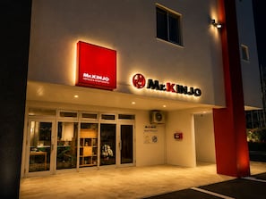 A hotel entrance with a prominent red sign, glass doors, and a visible fire alarm. - Mr.KINJO Miyakojima Aparagi Resort 1 (Miyakojima)