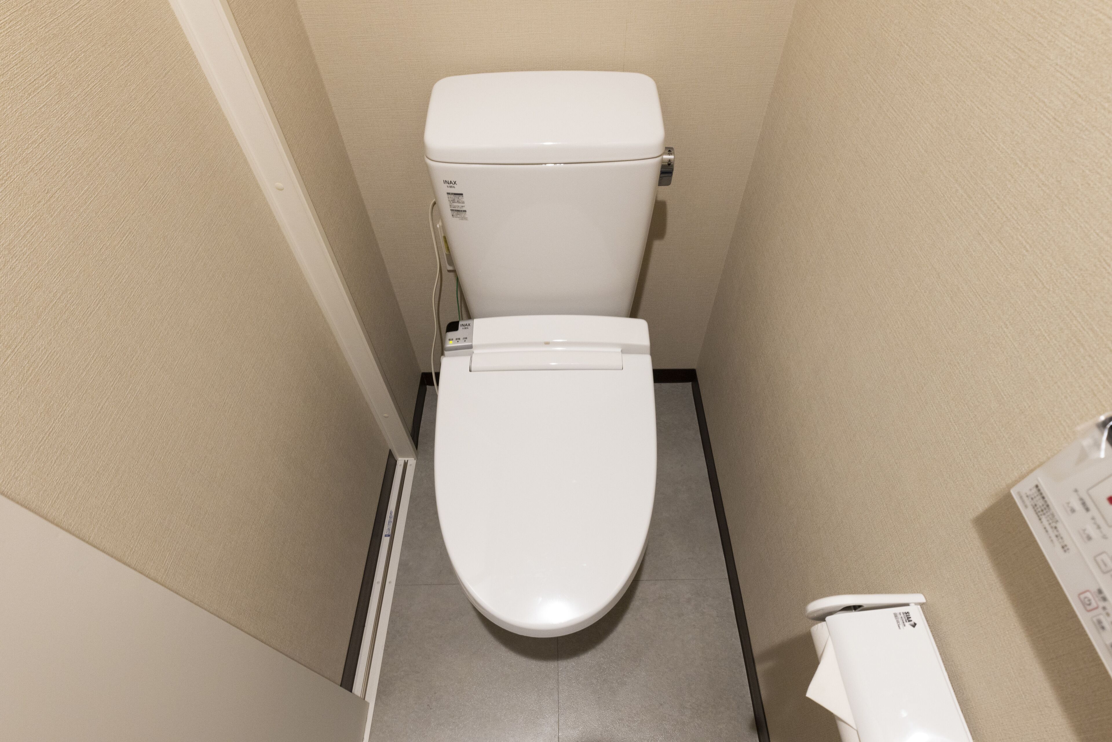 Une petite salle de bain étroite avec des toilettes et un bidet, tous deux blancs.