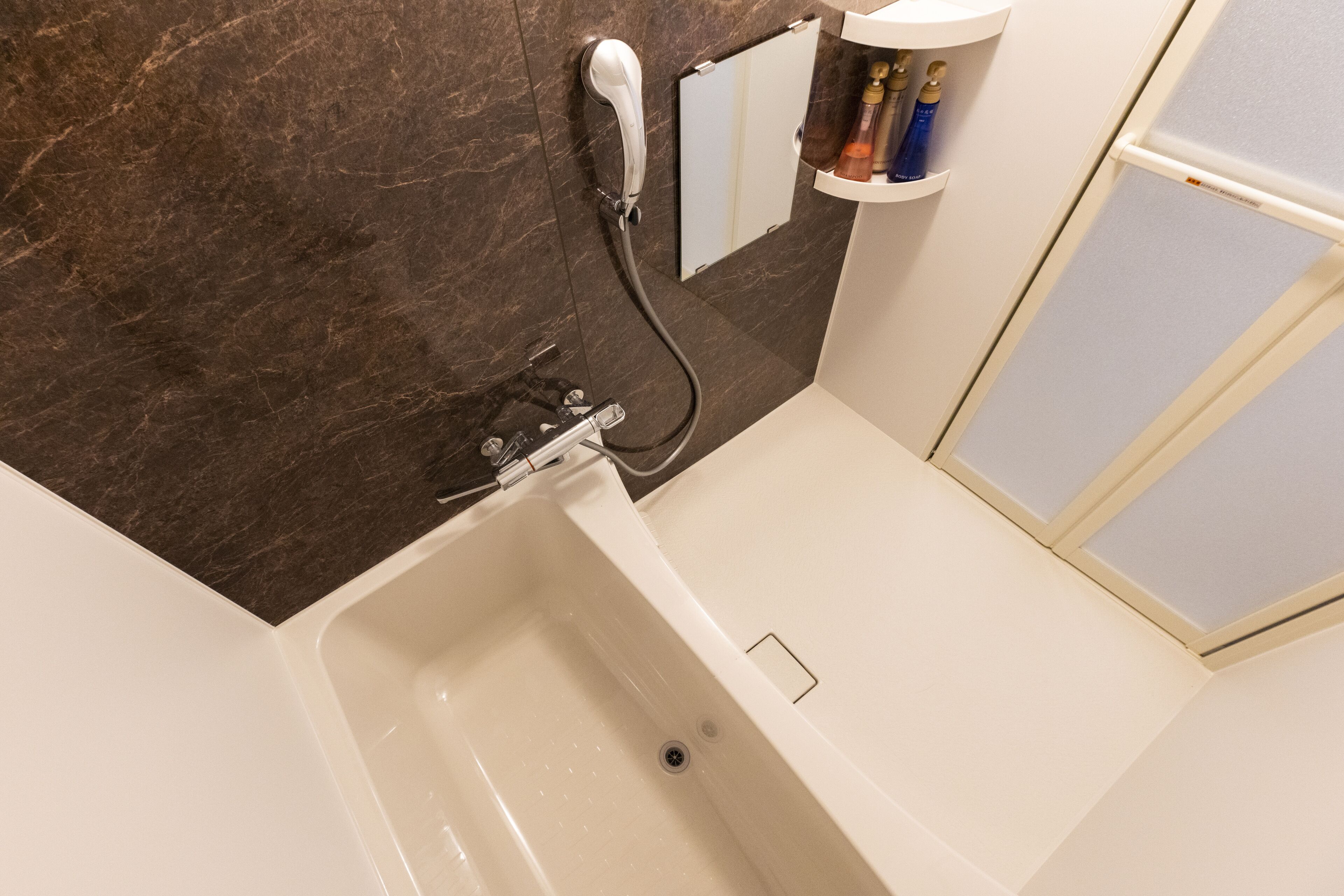 A bathroom with a bathtub, a shower, and a mirror.