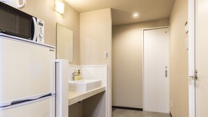 A compact hotel room with a kitchenette, a sink, and a door leading to another room. - Mr.KINJO Miyakojima Aparagi Resort 1 (Miyakojima)