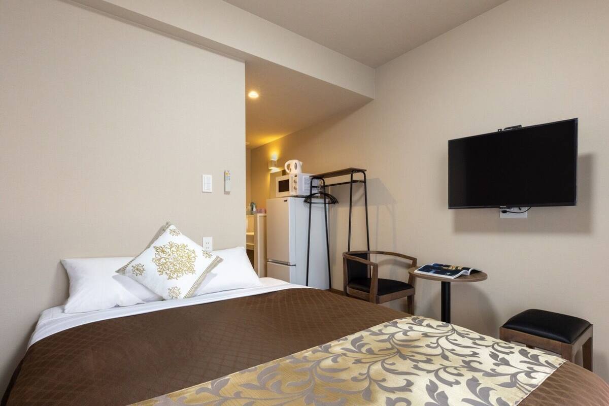 A hotel room with a bed, a TV, a desk, and a chair.