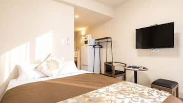 A hotel room with a bed, a TV, a small table, and a chair.