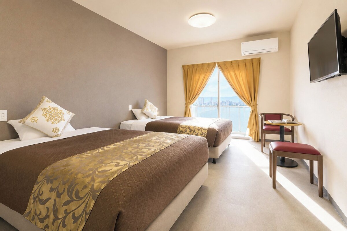 Une chambre d’hôtel avec deux lits, un bureau, une chaise et un téléviseur.