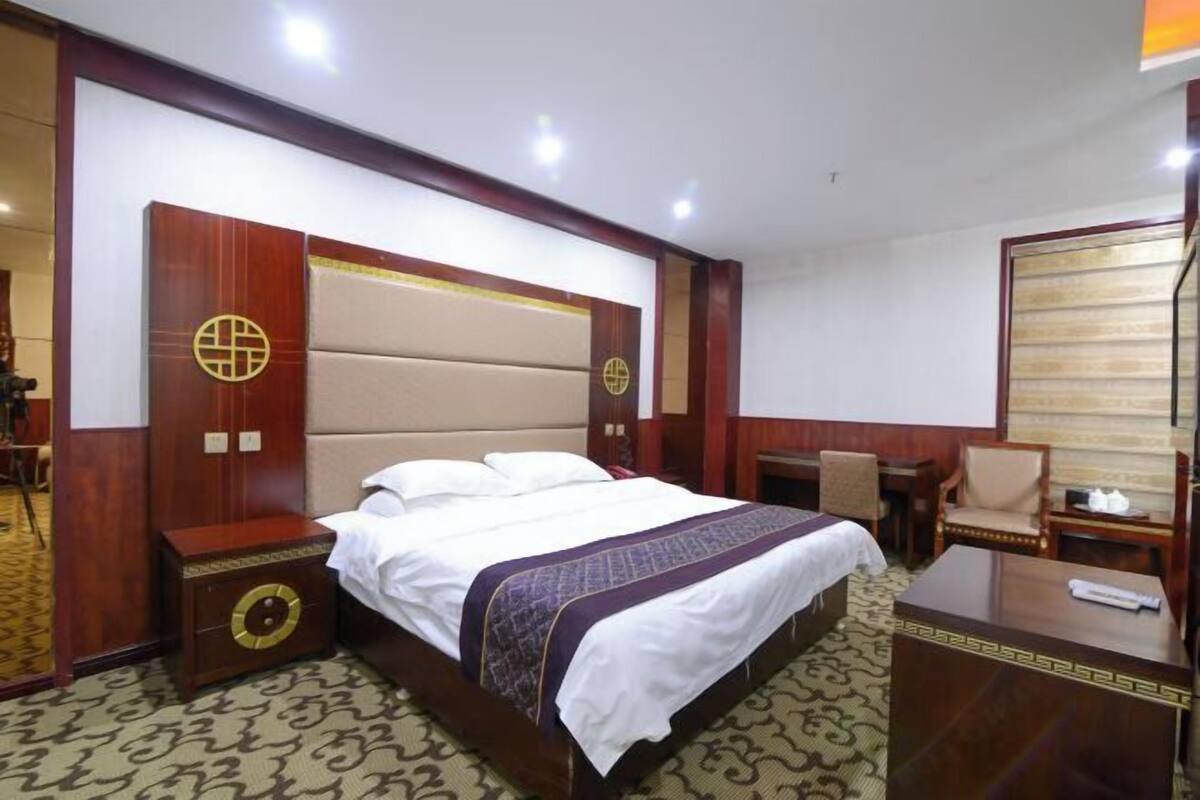 Ein Hotelzimmer mit einem großen Bett, einem Schreibtisch, einem Stuhl und einem Kleiderschrank.