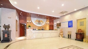 A hotel reception area with a marble floor, a reception desk, and a large emblem above the desk. - Zhouzai Hotel (Yangzhong)