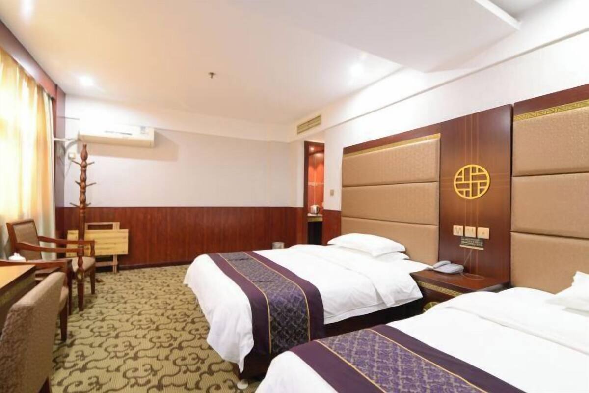 Ein Hotelzimmer mit zwei Betten, einem Schreibtisch, einem Stuhl und einem kleinen Tisch.