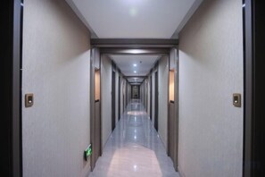 A long, narrow hallway with doors on both sides, leading to rooms. - Zhouzai Hotel (Yangzhong)