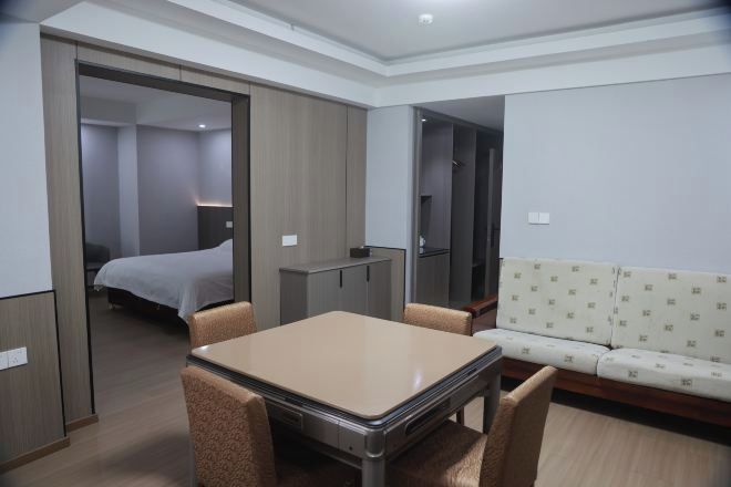 A hotel room with a bed, a table, chairs, a sofa, and a wardrobe.