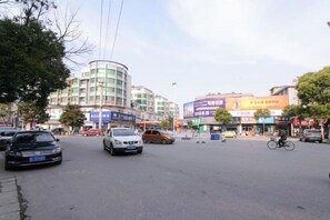 A street scene with buildings, cars, and a cyclist. - Zhouzai Hotel (Yangzhong)