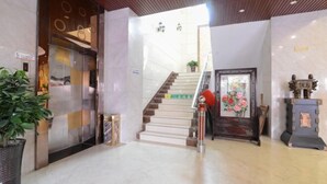 A hotel lobby with a marble floor, a staircase, a reception desk, and a potted plant. - Zhouzai Hotel (Yangzhong)