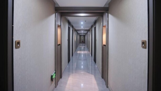 A long, narrow hallway with a polished floor and walls, leading to a door at the end. - Zhouzai Hotel (Yangzhong)