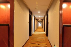 Un pasillo de hotel con piso alfombrado, paredes de madera y puertas a ambos lados.