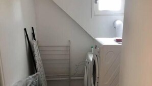 A small laundry room with a washing machine, a drying rack, and a window. - "L'Historique": House 2 minutes' walk from the center (Bayeux)