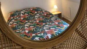 A cozy attic bedroom with a bed, a small table, and a lamp. - "L'Historique": House 2 minutes' walk from the center (Bayeux)