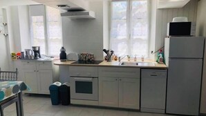 A modern kitchen with a built-in oven, a sink, and a refrigerator. There is a window providing natural light and a view of the outdoors.