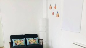 A modern living room with a black sofa, two yellow ottomans, a wooden coffee table, and a whiteboard on the wall.