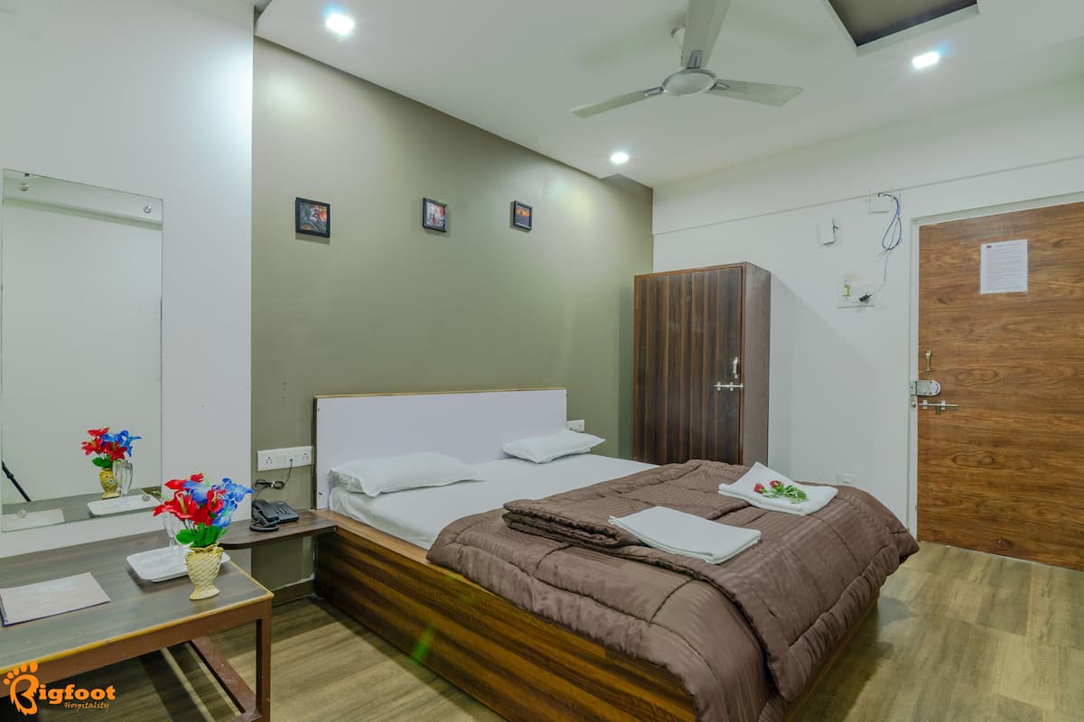 Habitación de hotel con cama, mesita de noche y espejo.
