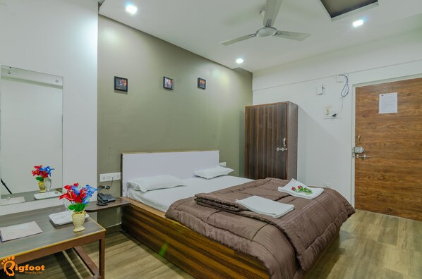Habitación de hotel con cama, mesita de noche y espejo.