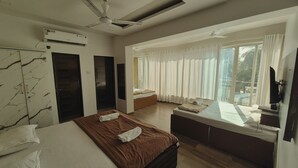 Une chambre d’hôtel moderne dotée d’un grand lit, d’un bureau, d’un ventilateur de plafond et offrant une vue sur l’extérieur.