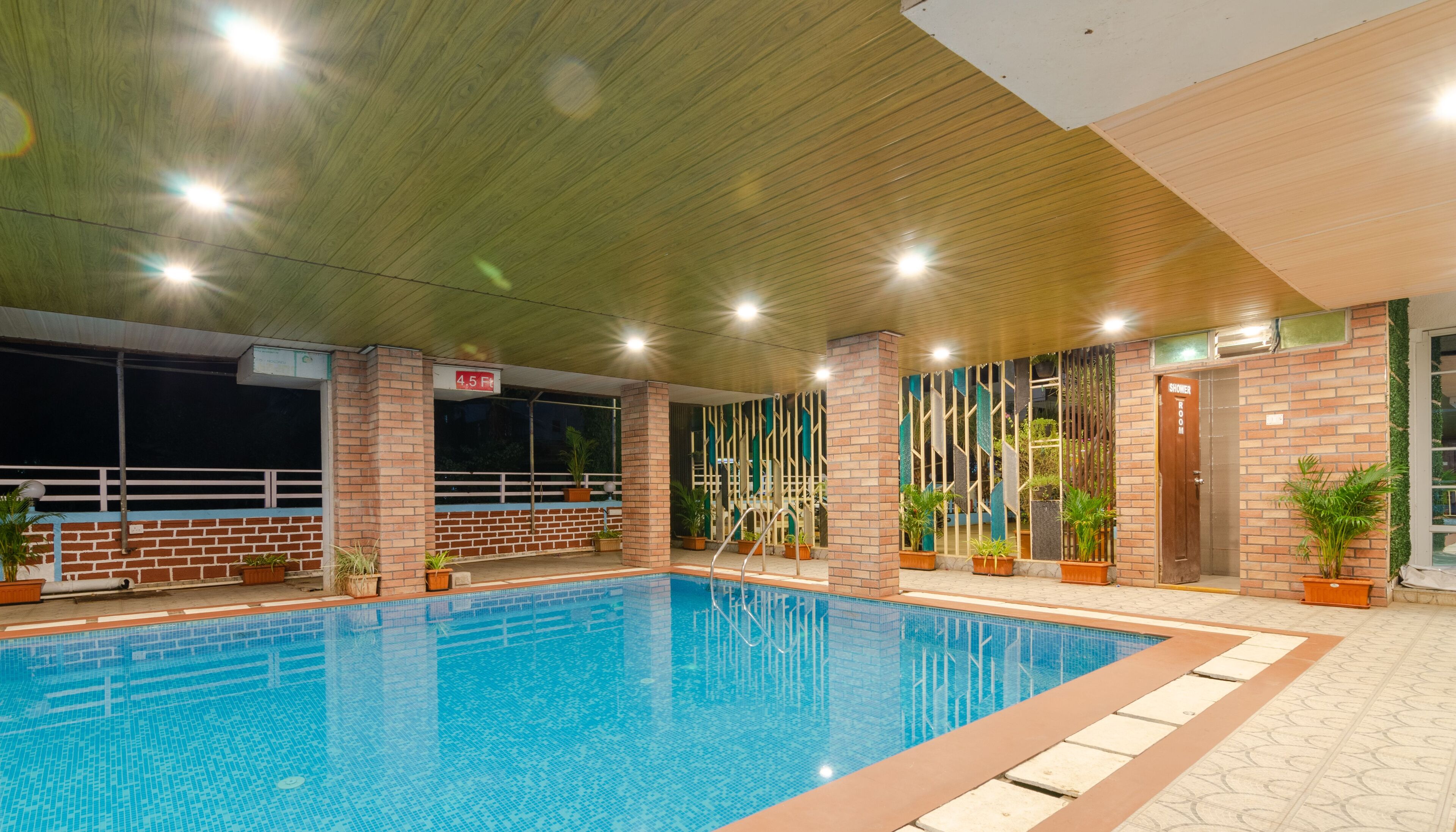 An indoor swimming pool with a tiled floor, surrounded by brick walls and wooden beams.