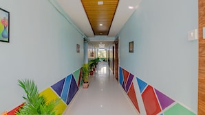 Un couloir doté d’un plafond en bois, d’un sol carrelé et de motifs géométriques colorés sur les murs.