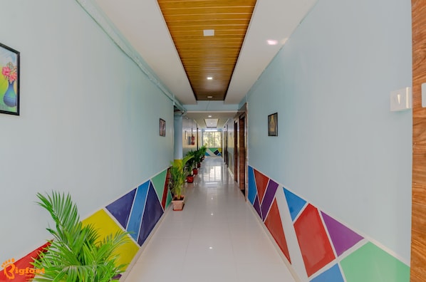 Un pasillo con techo de madera, suelo de baldosas y patrones geométricos coloridos en las paredes.