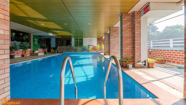 Une piscine intérieure à l’eau d’un bleu limpide, entourée de murs en briques et agrémentée de plantes en pot.