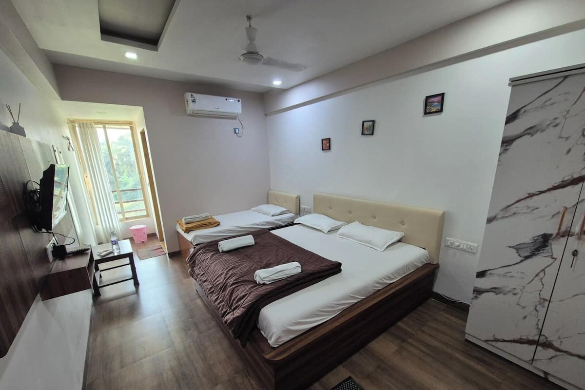 Habitación de hotel con cama, escritorio, silla, armario y ventilador de techo.