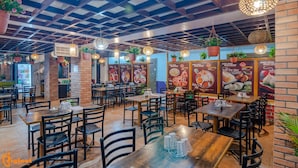 Un restaurant aux murs de briques, aux tables en bois et aux plantes suspendues.
