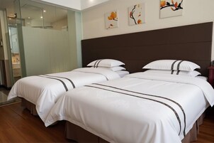 Habitación de hotel con dos camas, cabecera oscura y una obra de arte en la pared.
