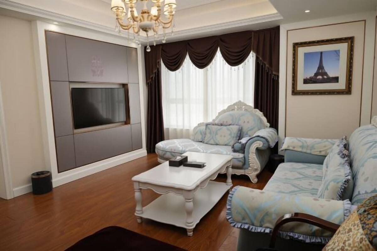 Una sala de estar con sofá, sillón, televisor y candelabro.