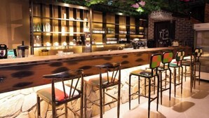 Eine Bar mit einer langen Theke, Regalen voller Flaschen und Barhocker.