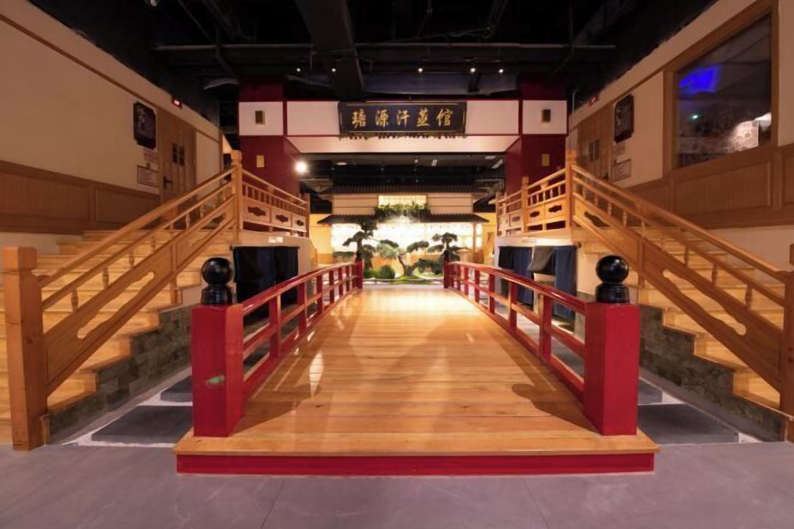 Un pont en bois, doté de rampes rouges, mène à l’intérieur d’un restaurant chinois traditionnel.