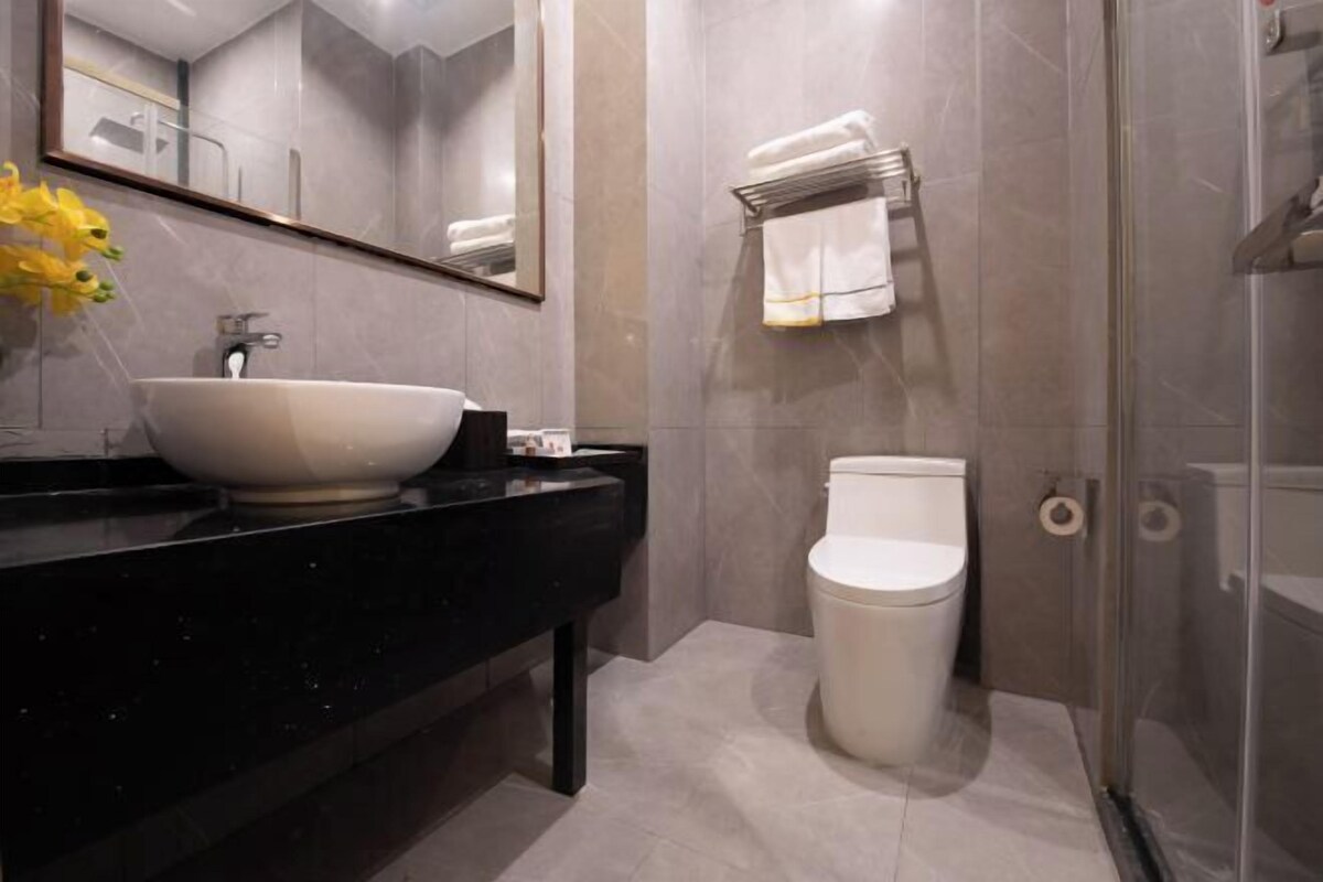 A modern bathroom with a large mirror, a vessel sink, a toilet, and a glass shower enclosure.