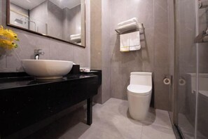A modern bathroom with a large mirror, a vessel sink, a toilet, and a glass shower enclosure. - Aurelian Haven Hotel (Hangzhou)