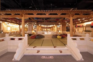 Un interior japonés tradicional con suelo de tatami, pilares de madera y una zona de estar central con tatami.