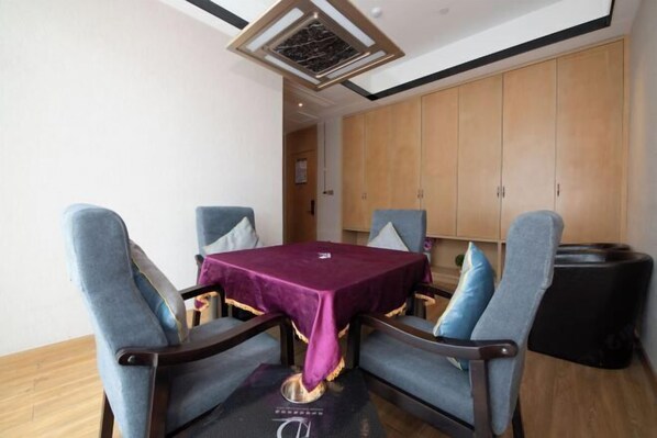 A dining area with a table covered in a purple tablecloth, surrounded by four chairs with blue upholstery. - Aurelian Haven Hotel (Hangzhou)