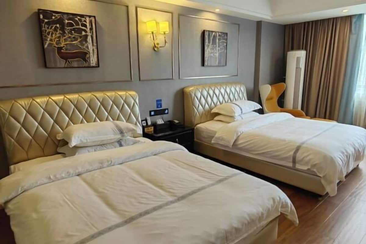 A hotel room with two beds, a nightstand, a lamp, and artwork on the walls.