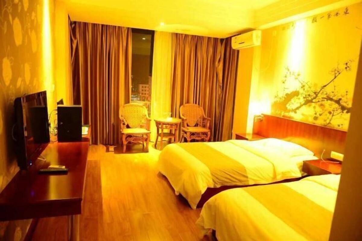 A hotel room with a bed, a desk with a computer, a chair, and a television.