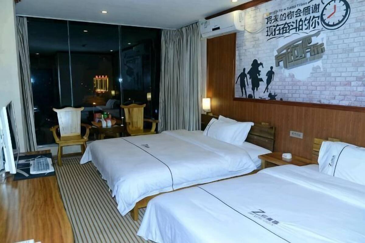 A hotel room with two beds, a desk, a chair, and a large window.